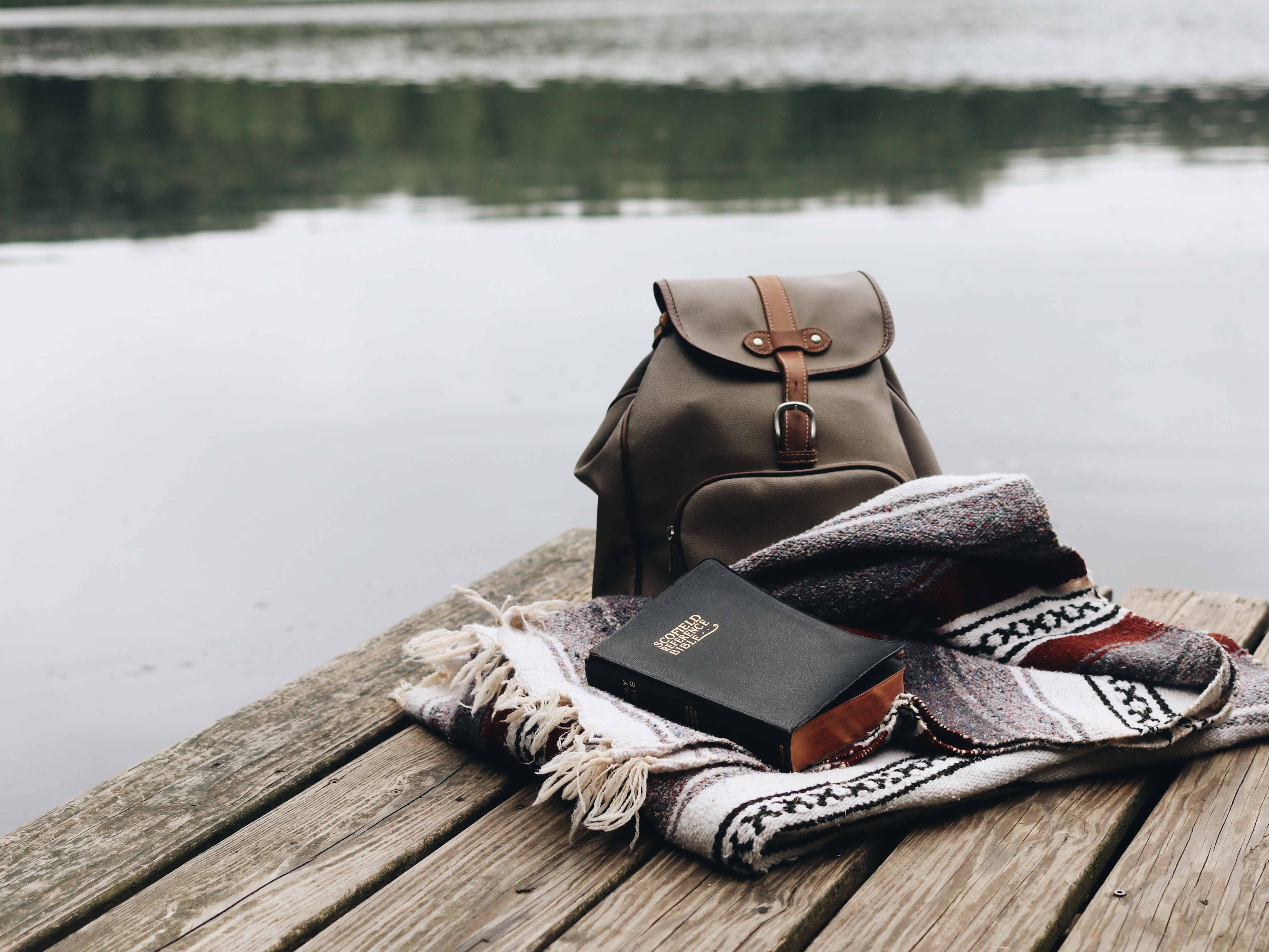 A backpack, blanket and book on a dock